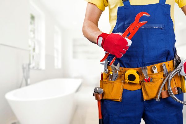 An emergency plumber holds their tools in a bathroom