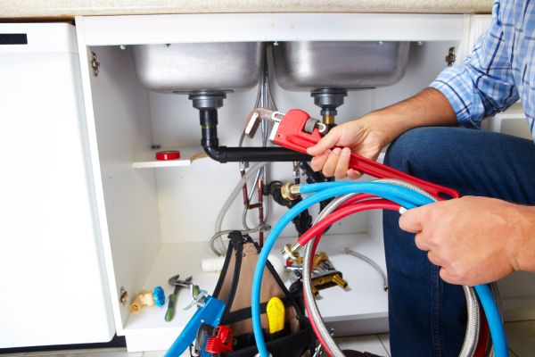 Emergency plumbing being done beneath a sink