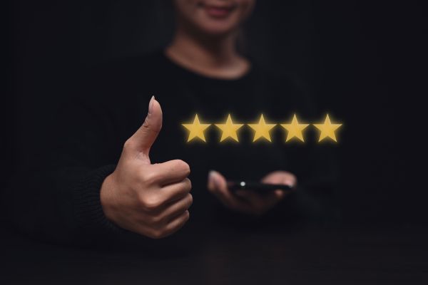 A woman does a thumb-up next to five stars above a cell phone